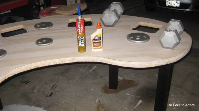 Next I used wood glue to glue in the dowel rods and then Liquid Nails to secure the legs to the table.  I used weights to make sure it went down properly.  I let this sit overnight to cure. 